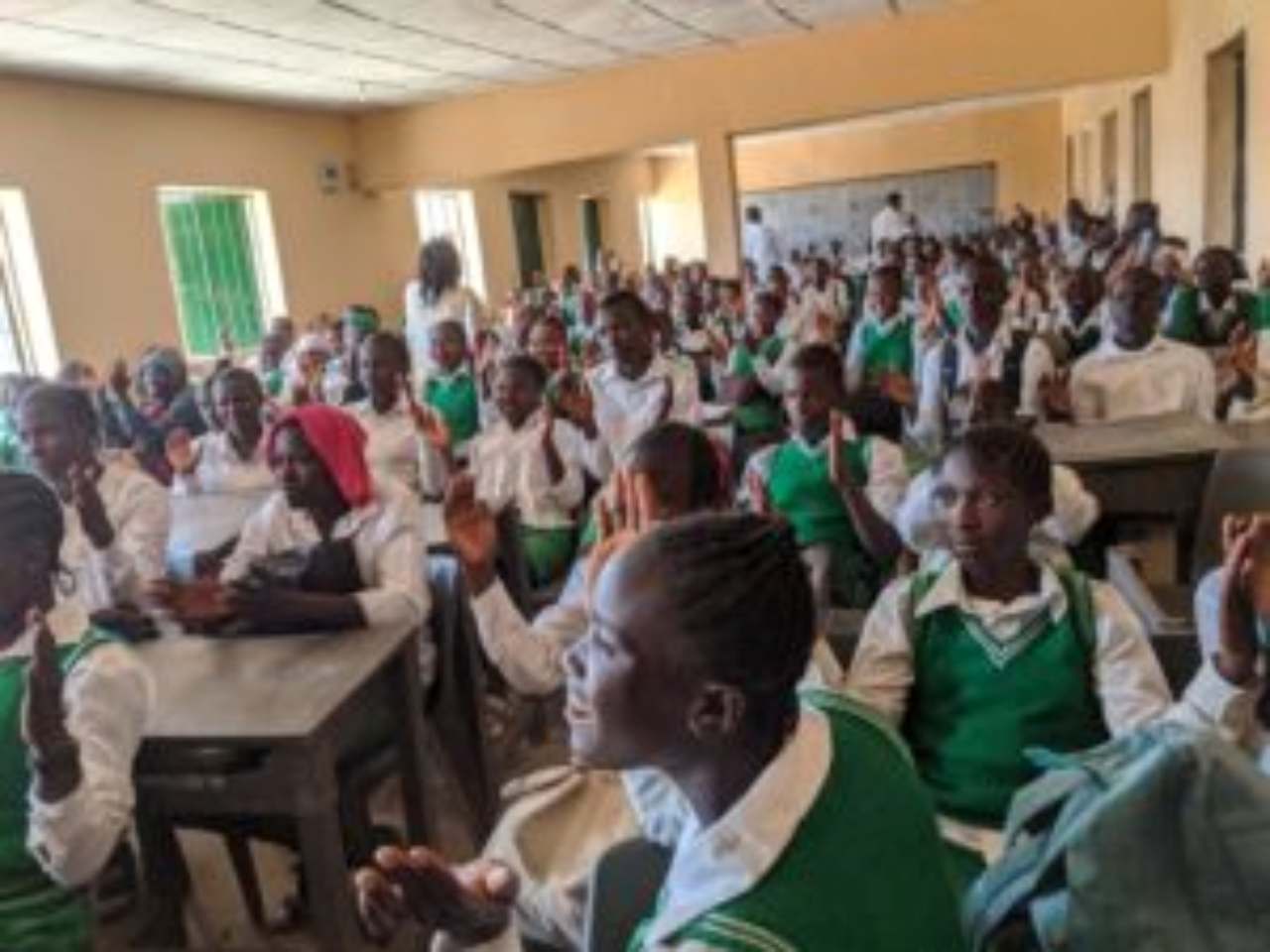 Children in green school uniforms learning in class